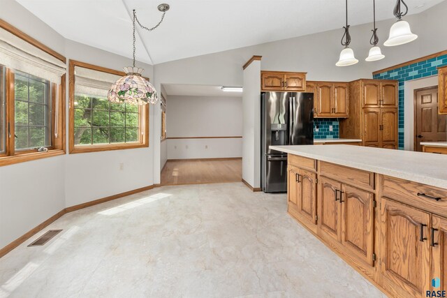 4220 S Minnesota Ave Unit 206, Sioux Falls, SD 57105 - kitchen with vaulted ceiling, stainless steel fridge with ice dispenser, brown cabinets, light countertops, and hanging light fixtures