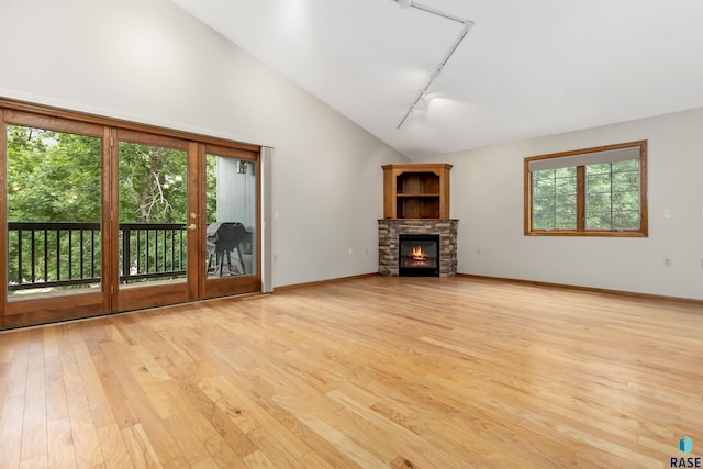 4220 S Minnesota Ave Unit 206, Sioux Falls, SD 57105 - unfurnished living room with rail lighting, light wood-type flooring, a stone fireplace, and high vaulted ceiling