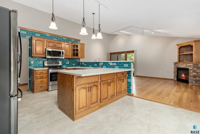 4220 S Minnesota Ave Unit 206, Sioux Falls, SD 57105 - kitchen featuring stainless steel appliances, backsplash, light countertops, brown cabinetry, and hanging light fixtures