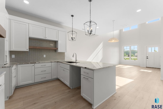 106 N Bryggen Pl, Sioux Falls, SD 57107 - kitchen with light wood-style flooring, tasteful backsplash, a peninsula, recessed lighting, and light stone counters