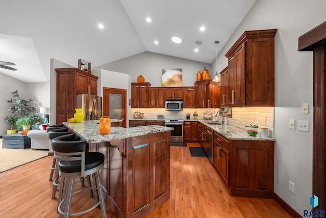 4400 E Aster Cir, Sioux Falls, SD 57103 - kitchen with stainless steel appliances, light stone counters, a center island, backsplash, and light wood-style flooring