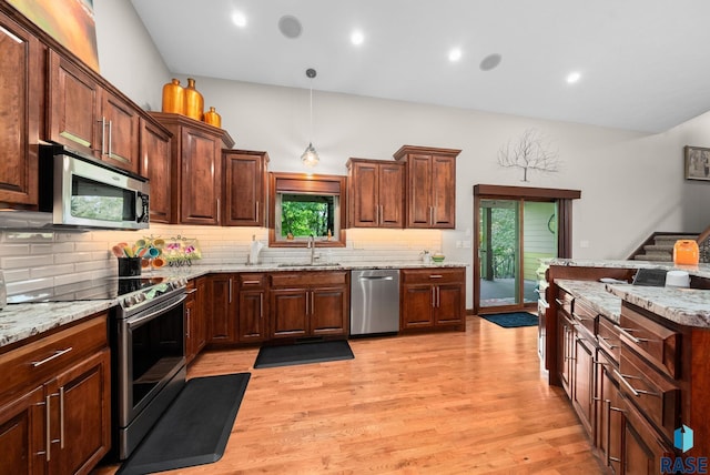 4400 E Aster Cir, Sioux Falls, SD 57103 - kitchen with appliances with stainless steel finishes, light wood-style floors, decorative backsplash, light stone countertops, and decorative light fixtures