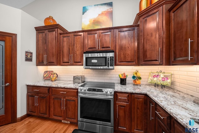 4400 E Aster Cir, Sioux Falls, SD 57103 - kitchen featuring appliances with stainless steel finishes, light wood-style flooring, backsplash, light stone countertops, and vaulted ceiling