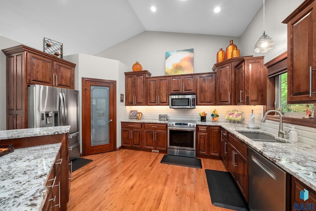 4400 E Aster Cir, Sioux Falls, SD 57103 - kitchen featuring appliances with stainless steel finishes, backsplash, light wood finished floors, light stone countertops, and decorative light fixtures