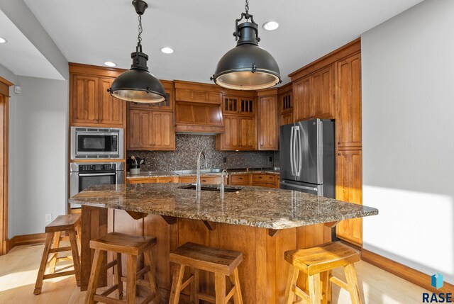 9005 E Torrey Pine Cir, Sioux Falls, SD 57110 - kitchen featuring appliances with stainless steel finishes, brown cabinets, backsplash, light wood-type flooring, and recessed lighting