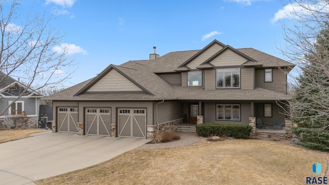 9005 E Torrey Pine Cir, Sioux Falls, SD 57110 - craftsman-style house with stone siding, a shingled roof, a garage, concrete driveway, and a chimney