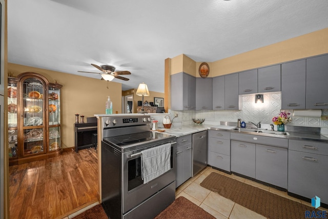 26045 485th Ave, Valley Springs, SD 57068 - kitchen featuring appliances with stainless steel finishes, gray cabinetry, backsplash, a ceiling fan, and a peninsula