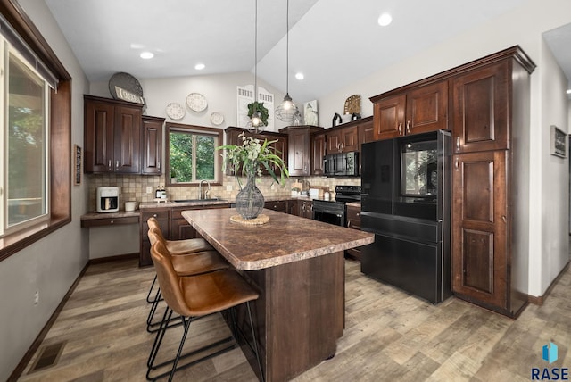 212 N Fairway Dr, Brandon, SD 57005 - kitchen with black appliances, dark brown cabinets, a center island, decorative backsplash, and lofted ceiling