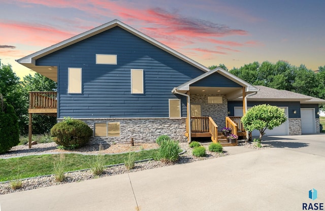212 N Fairway Dr, Brandon, SD 57005 - view of front of house with stone siding, driveway, an attached garage, and covered porch