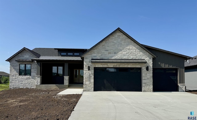 7300 E Misty Knoll Cir, Sioux Falls, SD 57110 - view of front of house with stone siding, a garage, a standing seam roof, concrete driveway, and board and batten siding
