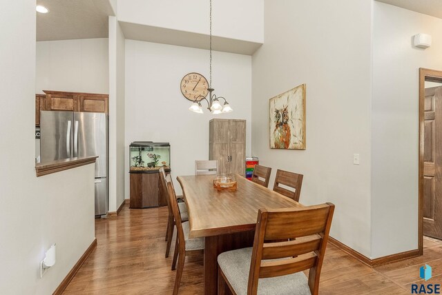 4005 S Grand Slam Ave, Sioux Falls, SD 57110 - dining room featuring light wood-type flooring, a chandelier, and a towering ceiling