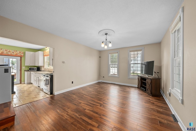 624 S 2nd Ave, Sioux Falls, SD 57104 - unfurnished living room featuring a chandelier, wood finished floors, healthy amount of natural light, and a textured ceiling