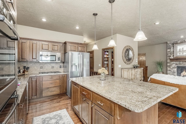 5809 S Nature Run Pl, Sioux Falls, SD 57108 - kitchen with stainless steel appliances, wood finished floors, a center island, light stone counters, and backsplash