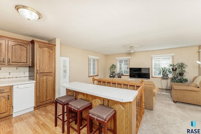 612 E 26th St, Sioux Falls, SD 57105 - kitchen with white dishwasher, tile countertops, open floor plan, a breakfast bar, and a center island