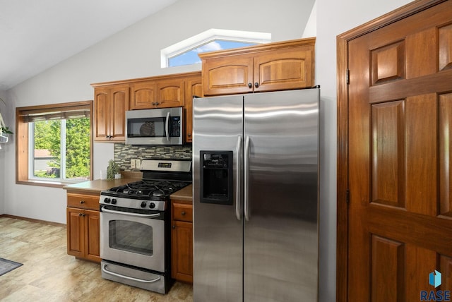 1413 Holbrook Ave, Sioux Falls, SD 57107 - kitchen with appliances with stainless steel finishes, vaulted ceiling, brown cabinetry, decorative backsplash, and dark countertops