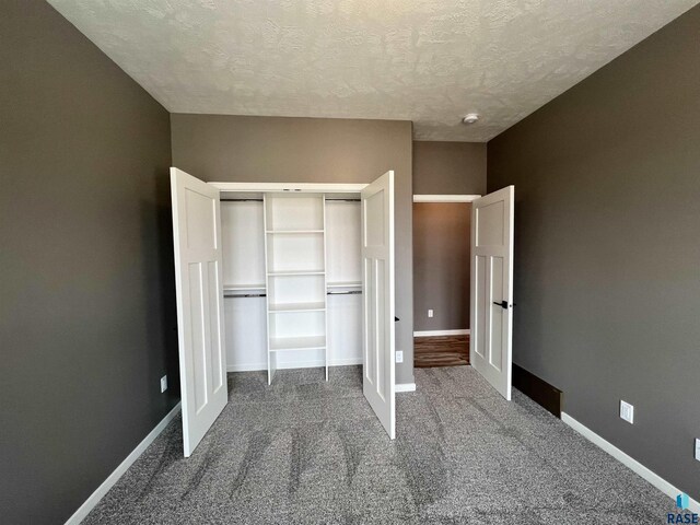 8105 W 24th St, Sioux Falls, SD 57106 - unfurnished bedroom featuring dark carpet, a textured ceiling, and a closet