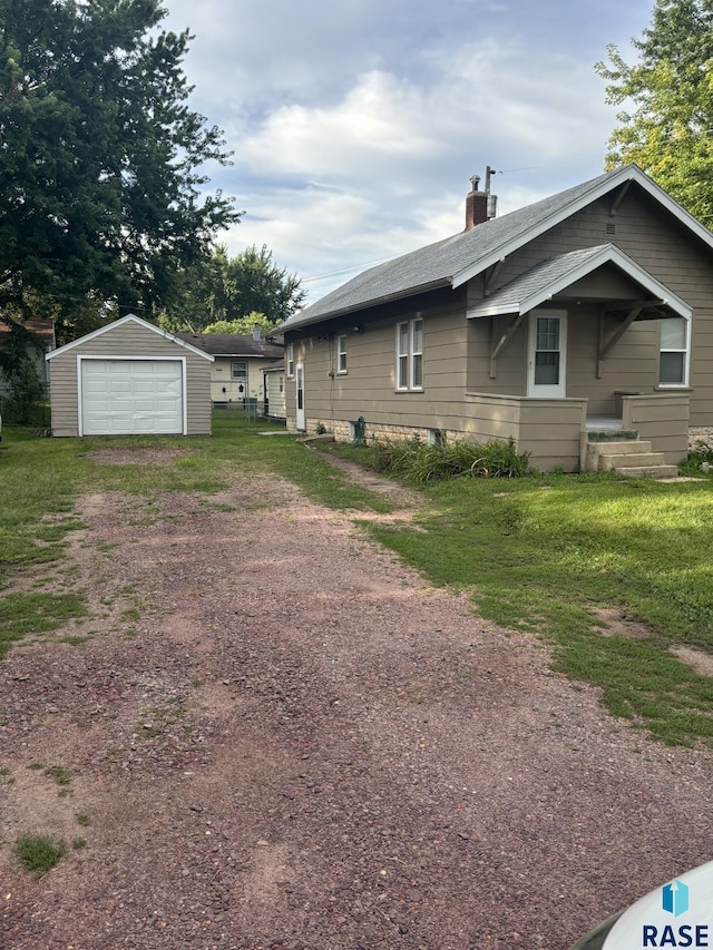 3605 E 12th St, Sioux Falls, SD 57103 - view of side of property with driveway, a garage, an outbuilding, and a chimney