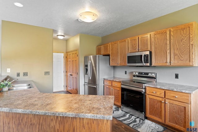 9232 W Norma Trl Unit 2, Sioux Falls, SD 57106 - kitchen with appliances with stainless steel finishes, a peninsula, light countertops, a textured ceiling, and wood finished floors
