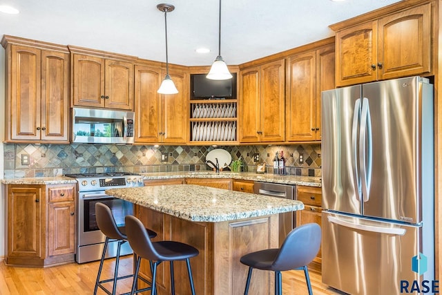 6500 E Split Rock Rd, Sioux Falls, SD 57110 - kitchen featuring appliances with stainless steel finishes, a breakfast bar area, brown cabinets, light wood-style floors, and tasteful backsplash