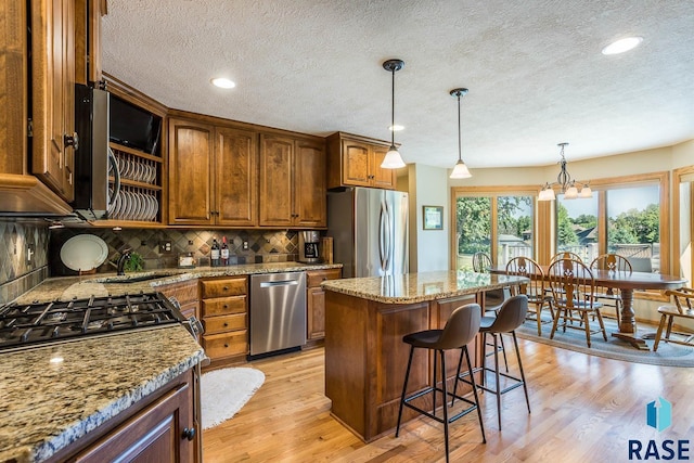 6500 E Split Rock Rd, Sioux Falls, SD 57110 - kitchen with stainless steel appliances, backsplash, a textured ceiling, light wood finished floors, and brown cabinets