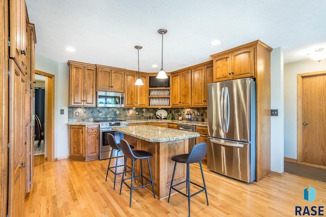 6500 E Split Rock Rd, Sioux Falls, SD 57110 - kitchen with appliances with stainless steel finishes, brown cabinets, a kitchen bar, light wood-type flooring, and recessed lighting
