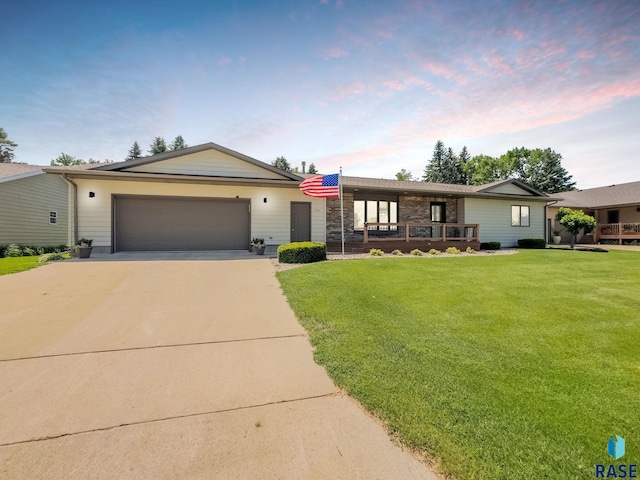 303 E 11th St, Dell Rapids, SD 57022 - ranch-style home featuring a garage, a lawn, concrete driveway, and covered porch