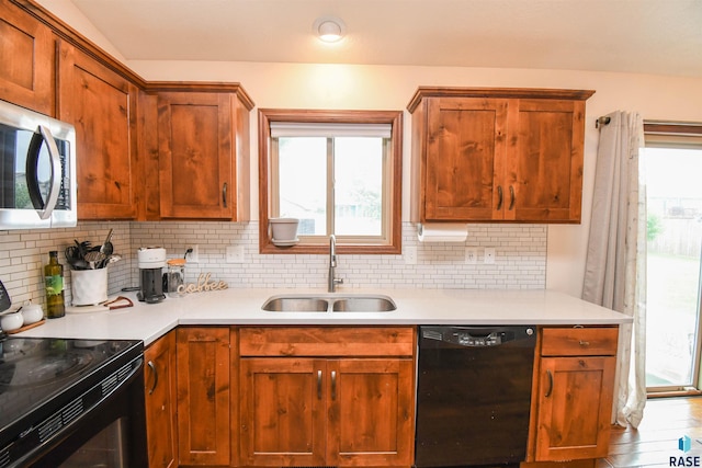 3208 S Triple Play Ave, Sioux Falls, SD 57110 - kitchen with black appliances, backsplash, light countertops, and brown cabinetry