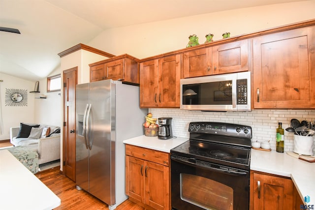 3208 S Triple Play Ave, Sioux Falls, SD 57110 - kitchen with stainless steel appliances, lofted ceiling, light countertops, light wood-style floors, and decorative backsplash