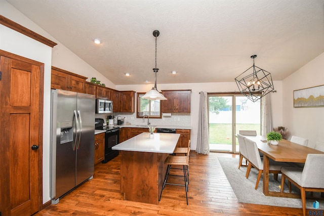 3208 S Triple Play Ave, Sioux Falls, SD 57110 - kitchen featuring stainless steel appliances, vaulted ceiling, tasteful backsplash, hardwood / wood-style floors, and light countertops