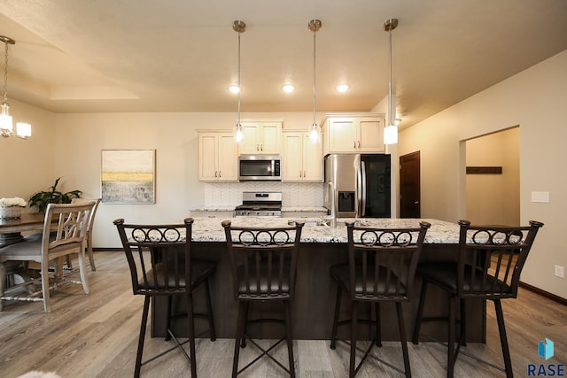 7905 S Brande Park Cir, Sioux Falls, SD 57108 - kitchen with appliances with stainless steel finishes, tasteful backsplash, a kitchen island with sink, and light wood-type flooring