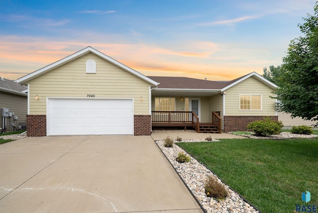 7020 W 53rd St, Sioux Falls, SD 57106 - ranch-style house with brick siding, an attached garage, concrete driveway, covered porch, and a front lawn