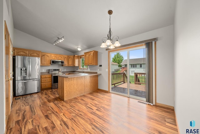 7020 W 53rd St, Sioux Falls, SD 57106 - kitchen with appliances with stainless steel finishes, wood finished floors, a peninsula, vaulted ceiling, and a chandelier
