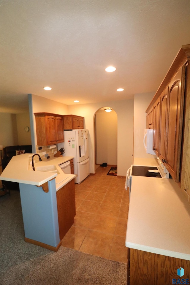 5708 S Shadow Wood Pl, Sioux Falls, SD 57108 - kitchen with white appliances, arched walkways, a peninsula, brown cabinets, and a breakfast bar area