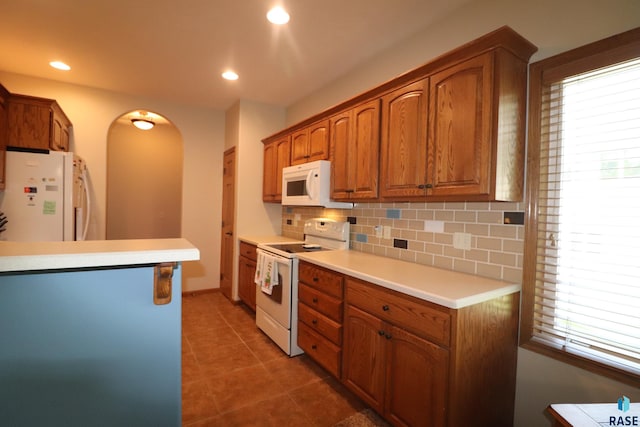 5708 S Shadow Wood Pl, Sioux Falls, SD 57108 - kitchen featuring white appliances, arched walkways, backsplash, plenty of natural light, and recessed lighting