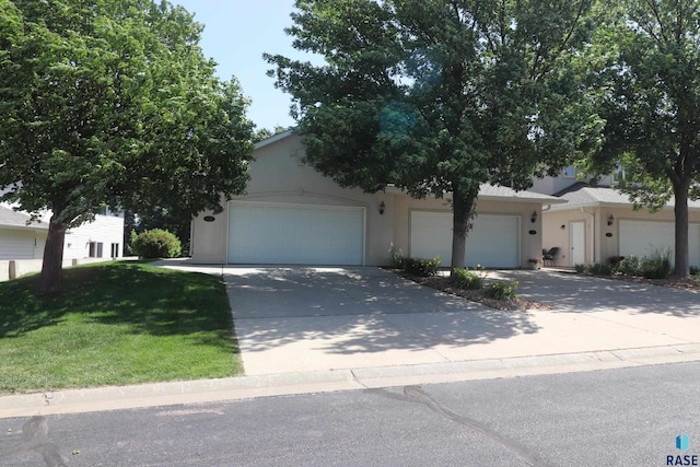 5708 S Shadow Wood Pl, Sioux Falls, SD 57108 - obstructed view of property featuring concrete driveway, stucco siding, a front yard, and an attached garage