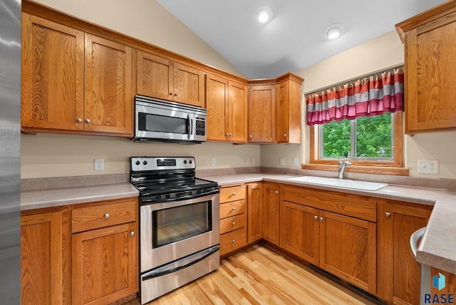 4912 E 42nd St, Sioux Falls, SD 57110 - kitchen with appliances with stainless steel finishes, vaulted ceiling, light countertops, light wood-type flooring, and brown cabinetry