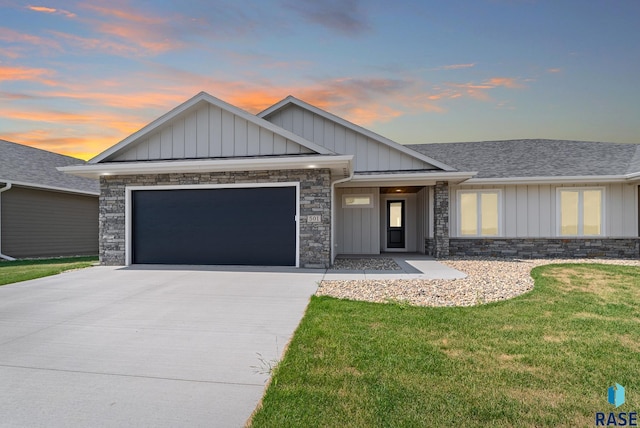 501 N Wildcat Dr, Sioux Falls, SD 57110 - view of front of house with board and batten siding, concrete driveway, a garage, stone siding, and a front lawn