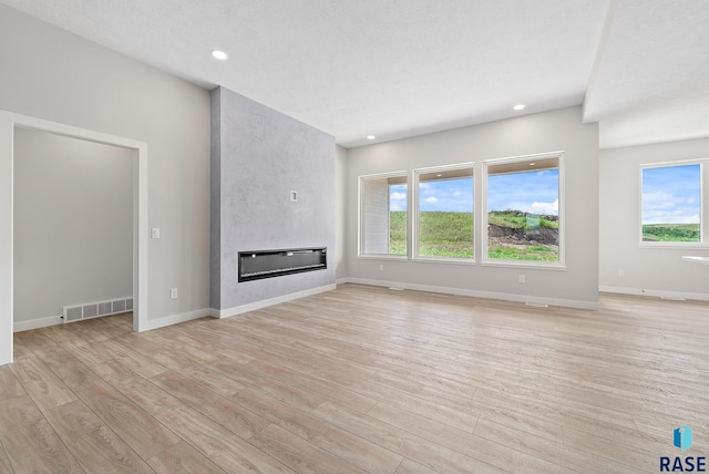 501 N Wildcat Dr, Sioux Falls, SD 57110 - unfurnished living room with light wood-style flooring, healthy amount of natural light, a large fireplace, and recessed lighting