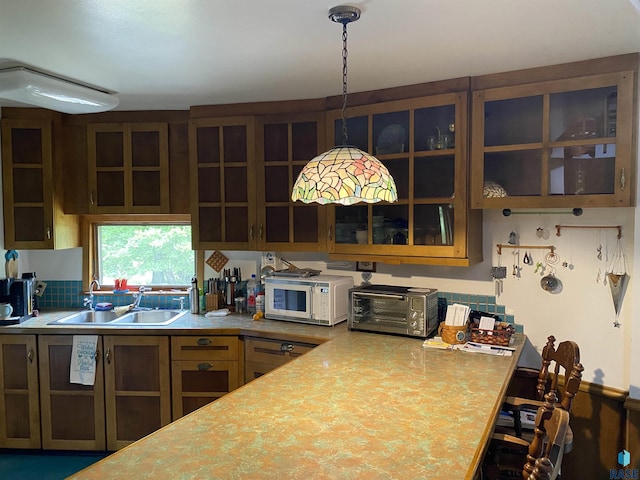 1496 121st St, Luverne, MN 56156 - kitchen with white microwave, light countertops, glass insert cabinets, and hanging light fixtures