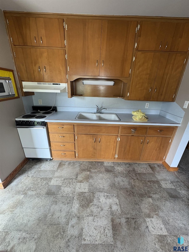 202 SW 7th Ave, Pipestone, MN 56164 - kitchen featuring under cabinet range hood, electric range, stone finish floors, brown cabinetry, and light countertops