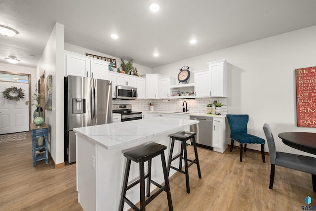 5402 S Bahnson Ave, Sioux Falls, SD 57108 - kitchen with appliances with stainless steel finishes, open shelves, light wood finished floors, white cabinetry, and decorative backsplash