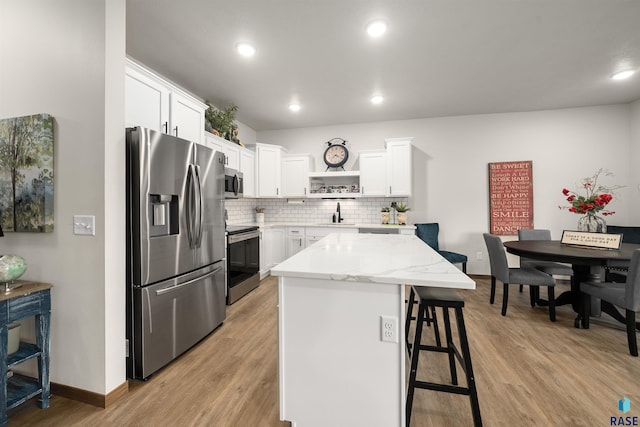 5402 S Bahnson Ave, Sioux Falls, SD 57108 - kitchen featuring appliances with stainless steel finishes, open shelves, a breakfast bar, white cabinetry, and backsplash