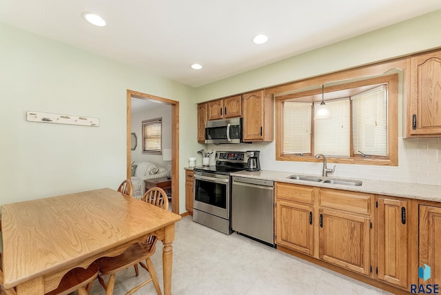 3112 E 15th St, Sioux Falls, SD 57103 - kitchen with appliances with stainless steel finishes, backsplash, brown cabinetry, light stone countertops, and recessed lighting