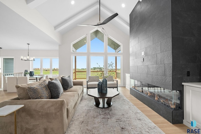 5601 E Morningside Cir, Sioux Falls, SD 57110 - living room with high vaulted ceiling, a tile fireplace, light wood-type flooring, a ceiling fan, and a chandelier