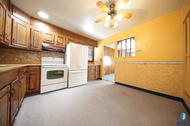 2312 E 19th St, Sioux Falls, SD 57103 - kitchen featuring white appliances, under cabinet range hood, light carpet, ceiling fan, and brown cabinets