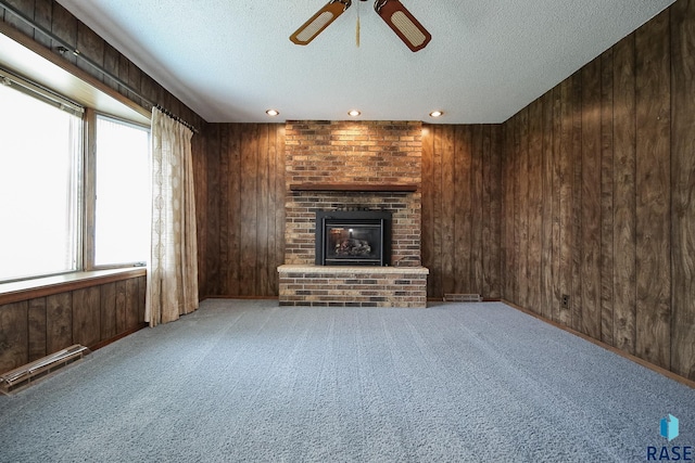 2312 E 19th St, Sioux Falls, SD 57103 - unfurnished living room featuring wood walls, a textured ceiling, a brick fireplace, ceiling fan, and carpet floors