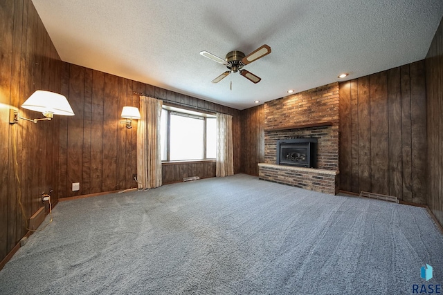 2312 E 19th St, Sioux Falls, SD 57103 - unfurnished living room with ceiling fan, a textured ceiling, a brick fireplace, carpet floors, and wooden walls