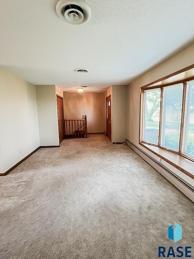 515 151st St, Luverne, MN 56156 - spare room featuring a baseboard heating unit, light carpet, and a textured ceiling
