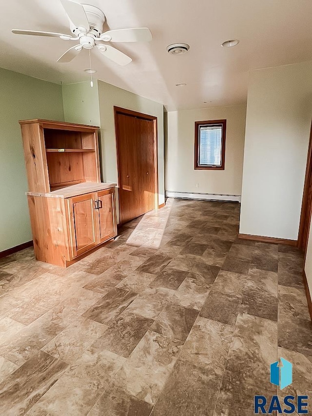 515 151st St, Luverne, MN 56156 - unfurnished living room featuring ceiling fan, a baseboard heating unit, and stone finish flooring