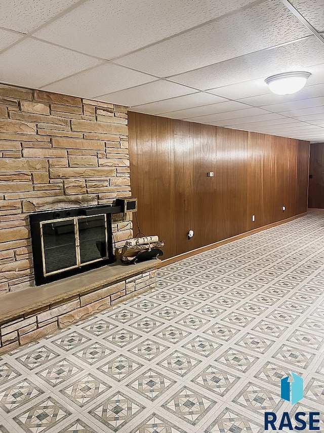 515 151st St, Luverne, MN 56156 - unfurnished living room with a fireplace, wood walls, and a drop ceiling